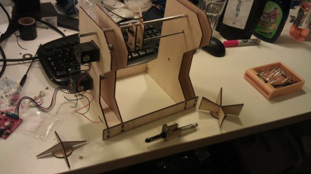 A collection of laser-cut bits of wood screwed together with some wire hanging off.