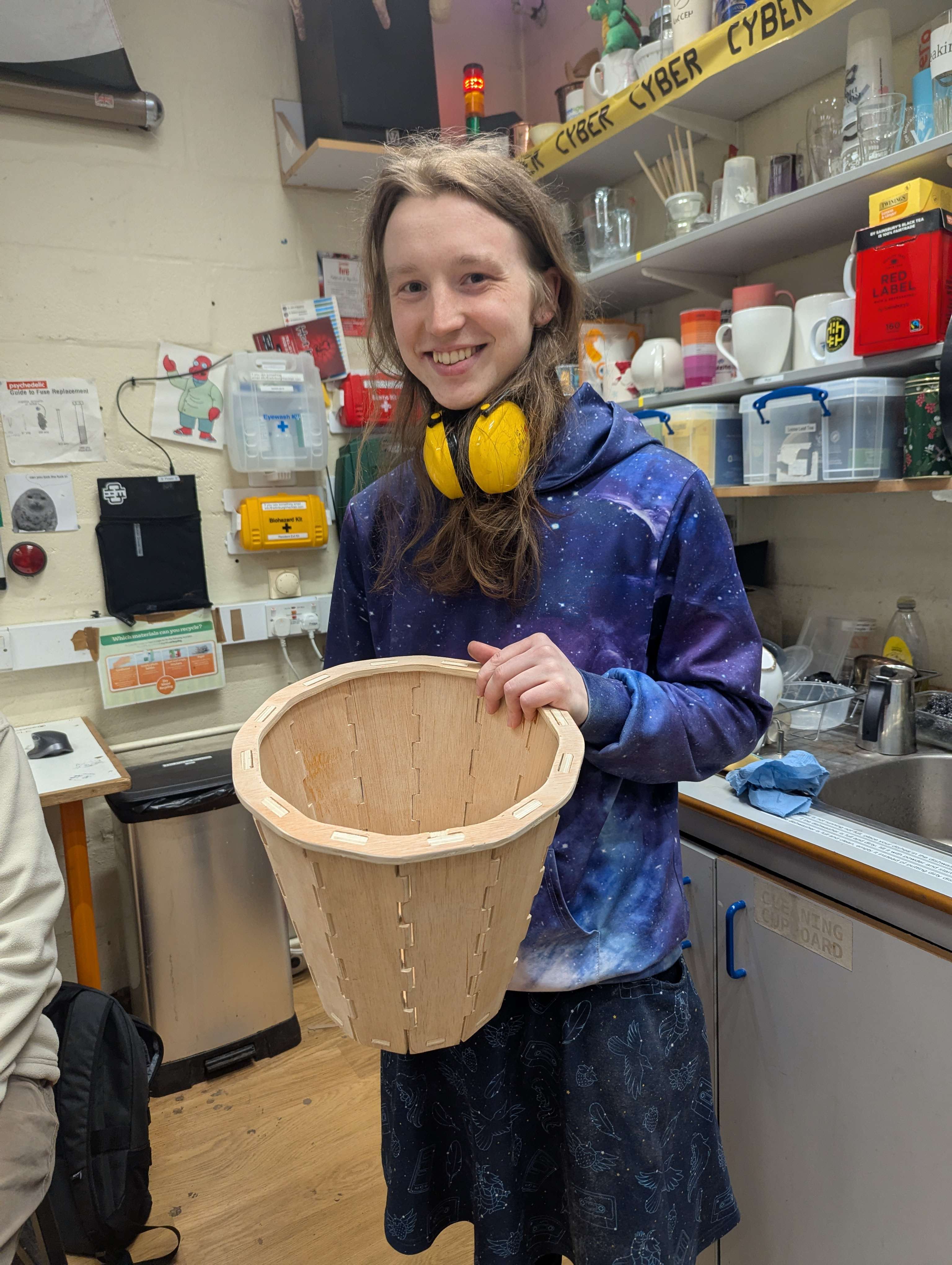 A person looking at the camera, holding a wooden basket.